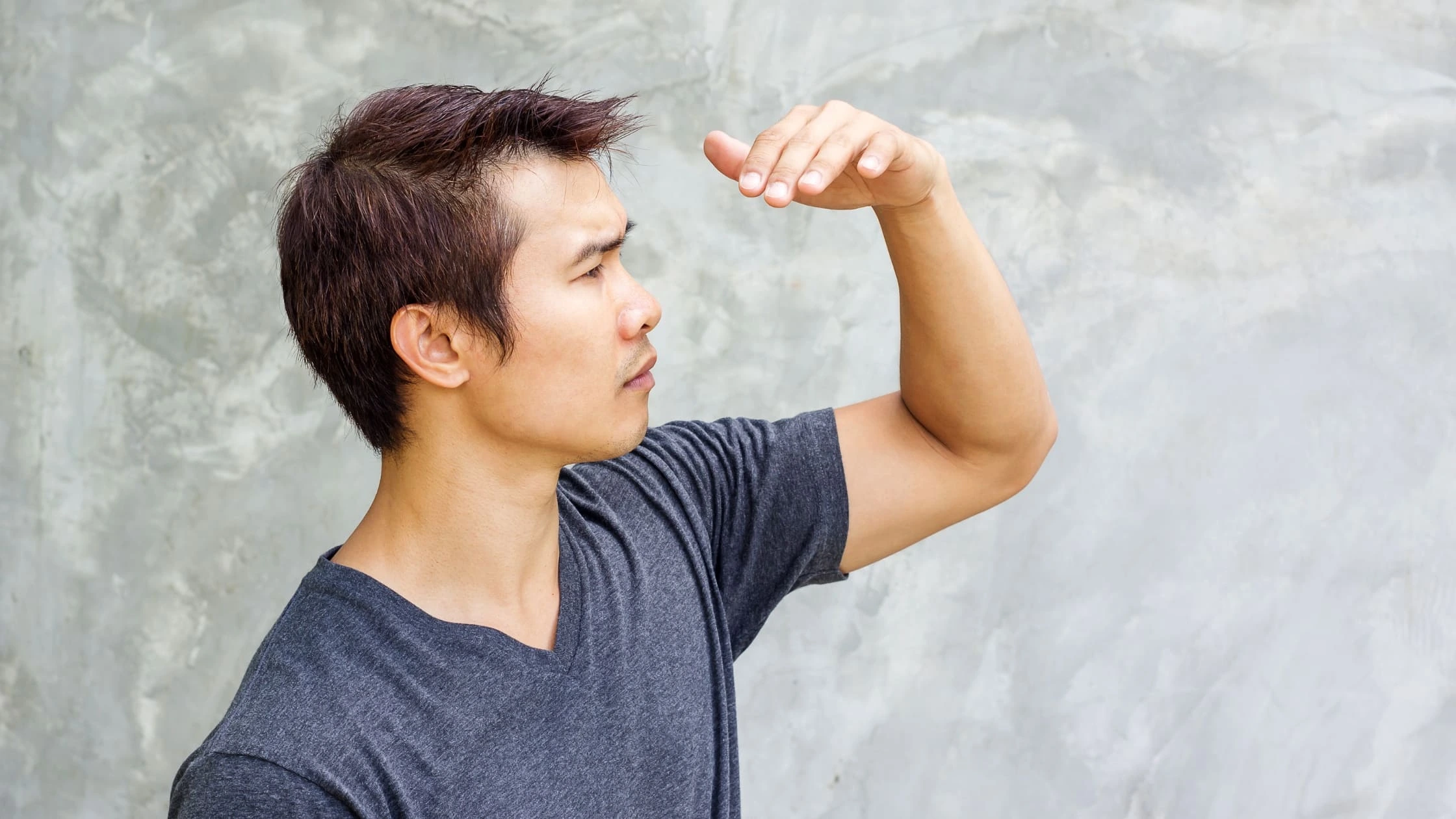 a young man squinting eyes from the direct sunlight